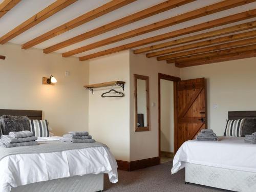 two beds in a room with wooden ceilings at The Granary in Hornsea