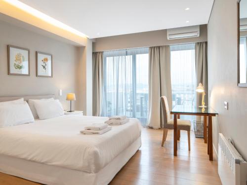 雅典的住宿－雅典市中心閣樓公寓，卧室配有白色的床、书桌和窗户。