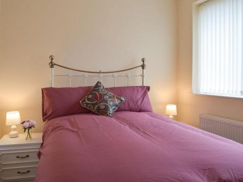 a bedroom with a large bed with purple sheets and pillows at Robins Nest in Samlesbury