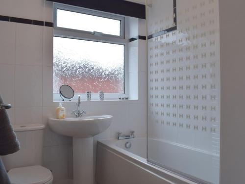 a bathroom with a sink and a toilet and a window at Robins Nest in Samlesbury