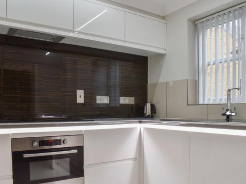 a kitchen with white cabinets and a sink and a window at Hollies Cottage 11 - Ukc4534 in Martock