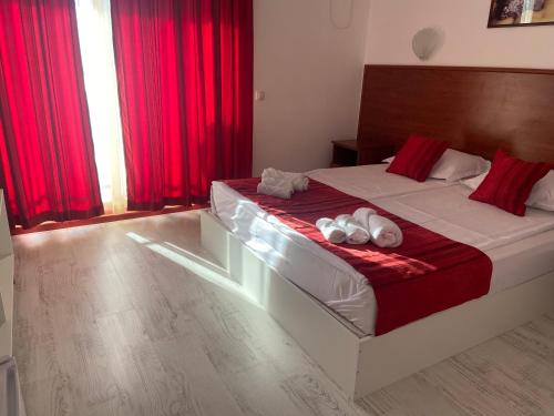 a bedroom with a large bed with red curtains at Ribarska Sreshta Family Hotel in Tsarevo
