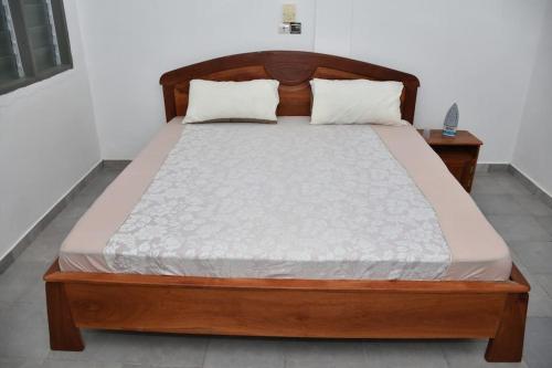 1 cama en un dormitorio con marco de madera en Tranquillité Cotonou en Cotonú