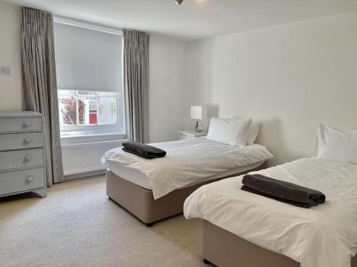 a white bedroom with two beds and a window at 7 Alfred Square in Deal