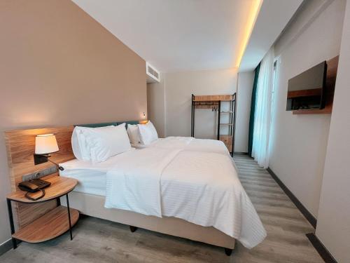 a bedroom with a large white bed and a lamp at Yalçındağ Otel Burdur in Burdur