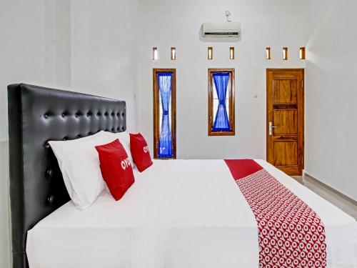 a bedroom with a bed with red and white pillows at Super OYO 92101 Elma Guesthouse in Yogyakarta