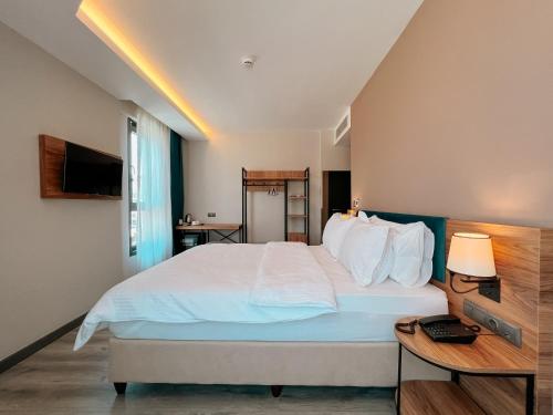 a bedroom with a large white bed and a table at Yalçındağ Otel Burdur in Burdur