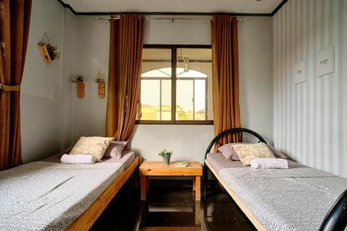 two beds in a room with a table and a window at Pallet Homes - Landheights in Iloilo City