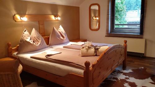 a bedroom with a wooden bed with pillows and a mirror at Haus Alpenblick in Obertraun