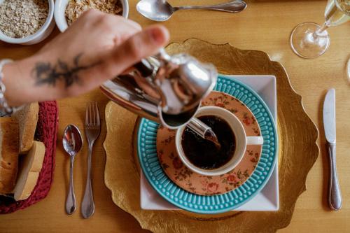 een persoon die koffie in een kopje op een tafel giet bij Carícia do Vento Pousada Boutique in Monte Verde
