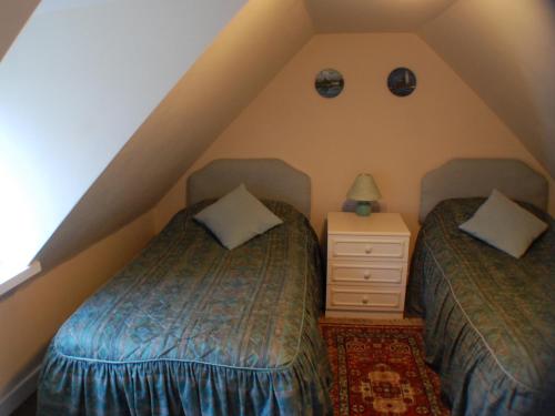 a attic bedroom with two beds and a night stand at Tigh Nan Eoin in Aultbea