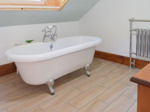 uma banheira branca na casa de banho com piso em madeira em Woodlands em Laugharne
