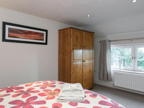 a bedroom with a bed and a cabinet and a window at The Old Rectory Cottage in Great Carlton