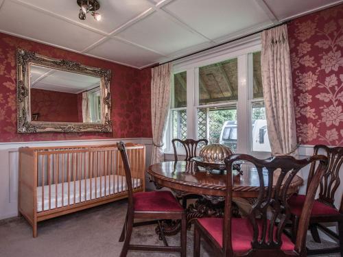 a dining room with a table and chairs and a crib at The Barn at Vine Cottage in Otley