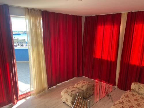 a bedroom with red curtains and a bed and a window at Ribarska Sreshta Family Hotel in Tsarevo