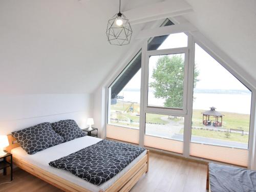 um quarto com uma cama e uma grande janela em Modern holiday homes directly on the lake in Kiedrowice em Kiedrowice