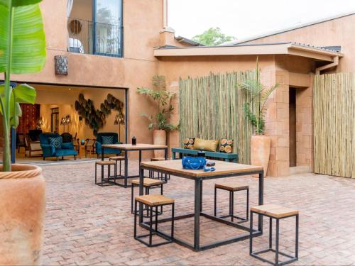 un patio avec des tables et des chaises en face d'un bâtiment dans l'établissement Tabokana House, à Victoria Falls