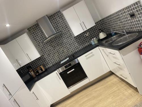Una cocina blanca con gabinetes blancos y un fregadero. en Beach House Courtyard 1 Bed, en Southport