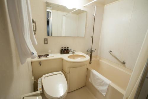 een badkamer met een toilet, een wastafel en een bad bij Green Rich Hotel Oita Miyakomachi in Oita