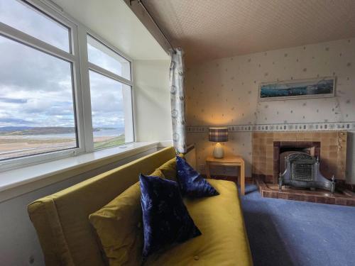 a living room with a yellow couch and a fireplace at Dalcharn in Invernaver
