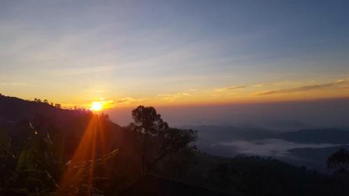 a sunset on top of a mountain with the sun setting at Bel View Guest House in Haputale