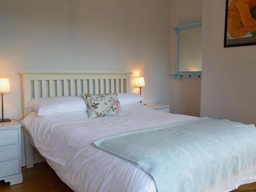 a white bed in a bedroom with two lamps at Eastwood Lodge in Bath