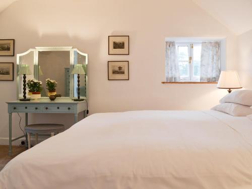 a bedroom with a white bed and a blue table at Garden Cottage in Strachur