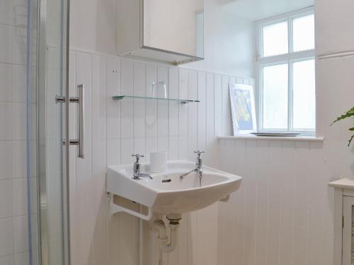 a white bathroom with a sink and a shower at Garden Cottage in Strachur