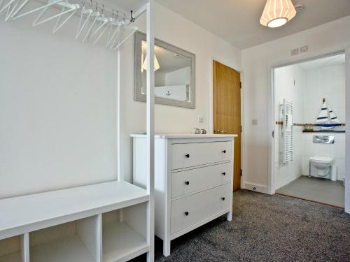 een slaapkamer met een witte dressoir en een spiegel bij Fistral Escape in Crantock