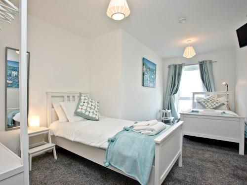een slaapkamer met een wit bed en een spiegel bij Fistral Escape in Crantock