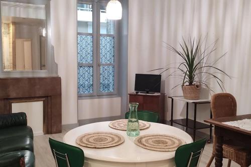 a living room with a table with green chairs at Appartement cosy à 2 pas des rues piétonnes in Chalon-sur-Saône