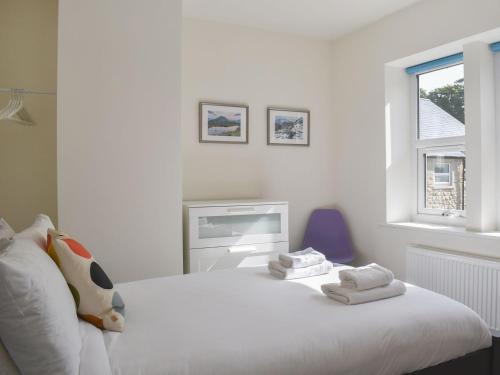 een witte slaapkamer met een wit bed en een raam bij Rose Cottage in Ingleton 