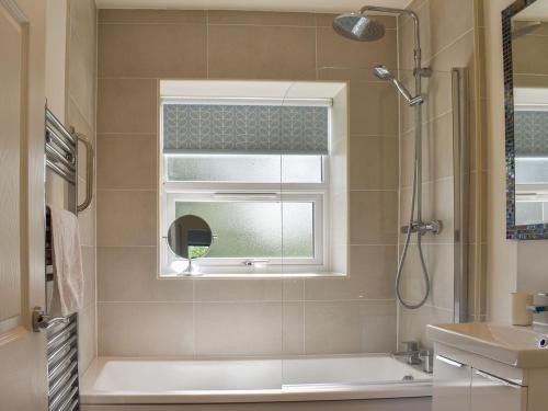 een badkamer met een douche, een wastafel en een spiegel bij Rose Cottage in Ingleton 