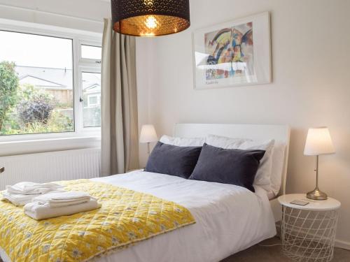 a bedroom with a bed with a yellow blanket and a window at Cartref in St. Davids