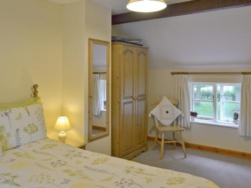 a bedroom with a bed and a window and a chair at Garden Farm Cottage in Ilam