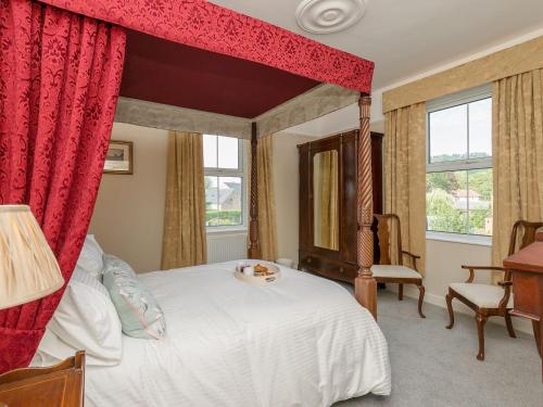 a bedroom with a canopy bed with red curtains at Haddon Villa in Bakewell