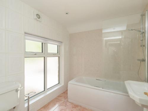 a white bathroom with a tub and a sink at Haddon Villa in Bakewell