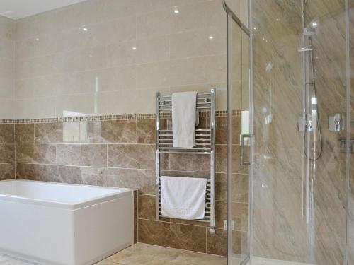 a bathroom with a shower and a tub and a sink at Liftingstane Cottage in Closeburn