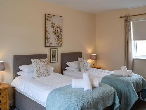 a bedroom with two beds with towels on them at Liftingstane Cottage in Closeburn