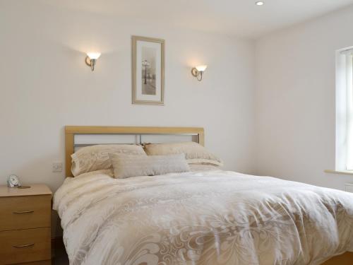 a bedroom with a large white bed with a wooden headboard at Mickle Hill Mews in Gargrave