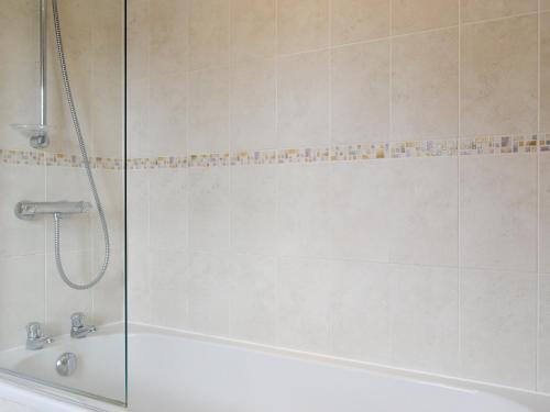 a shower with a glass door next to a bath tub at Mickle Hill Mews in Gargrave