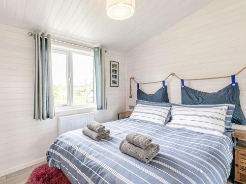 a bedroom with a blue and white bed with towels on it at Erica Lodge in Willington