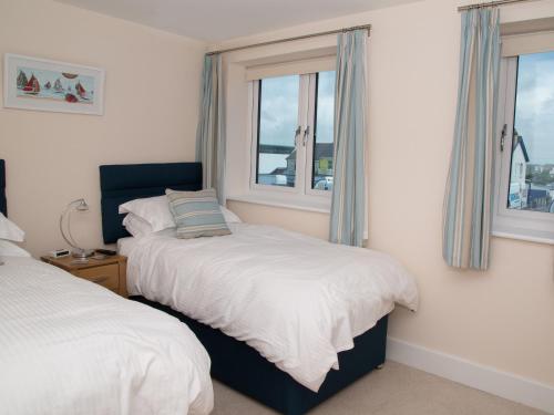 a bedroom with two beds and two windows at Apartment 5 Latitude 51 Westward Ho! in Westward Ho