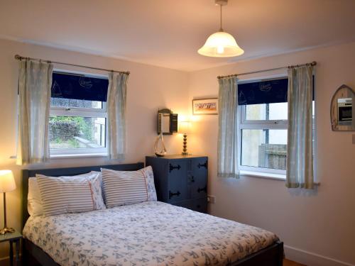 a bedroom with a bed and two windows at Farthings - 19292 in Bridport
