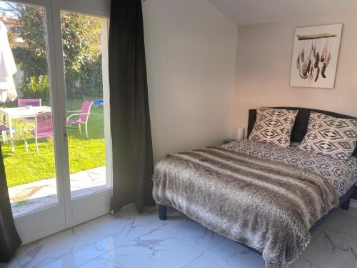um quarto com uma cama ao lado de uma porta de vidro deslizante em Studio climatisé avec piscine et jardin em Villeneuve-Loubet