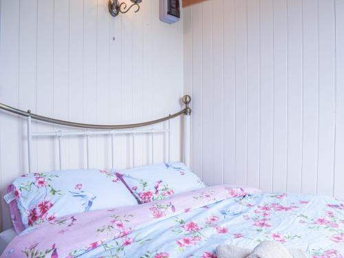 The Shearers Hut-uk39774 في Trefeglwys: غرفة نوم مع سرير مع زهور وردية عليه