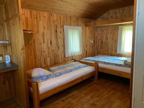 1 Schlafzimmer mit 2 Betten in einer Holzhütte in der Unterkunft Kurzemes pērle in Sepene