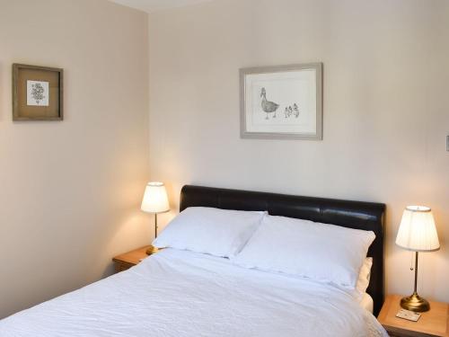 a bedroom with a white bed with two lamps at The Hollies in Bowness-on-Windermere