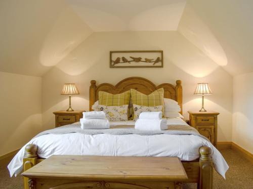 a bedroom with a large bed with two lamps at Deuchars Cottage in Kenmore