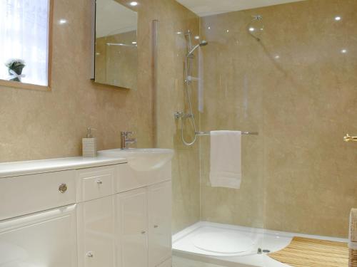 a bathroom with a shower and a sink and a mirror at Deuchars Cottage in Kenmore